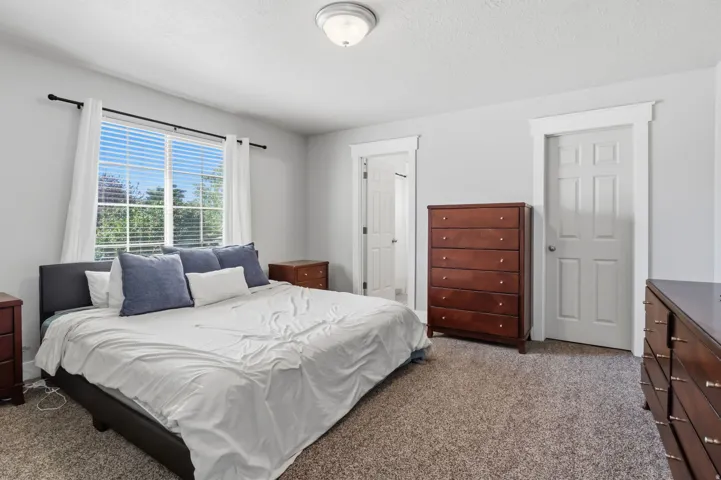 Carpeted flooring, window with blinds, panel doors, flush mount ceiling light
