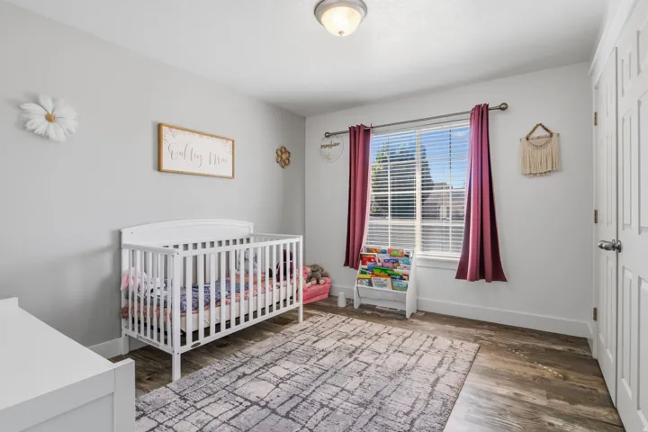 Wood-finish flooring, white trim, overhead lighting, and a paneled door