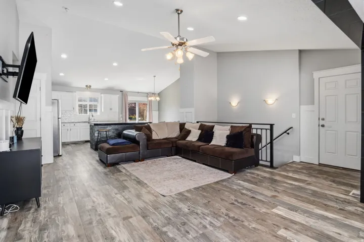 Vaulted ceiling with recessed lighting, wood-finish flooring, accent wall sconces, and white paneled door