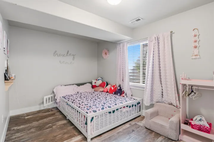 Wood-finish flooring with light gray walls, a window with horizontal blinds, and a flush mount ceiling light