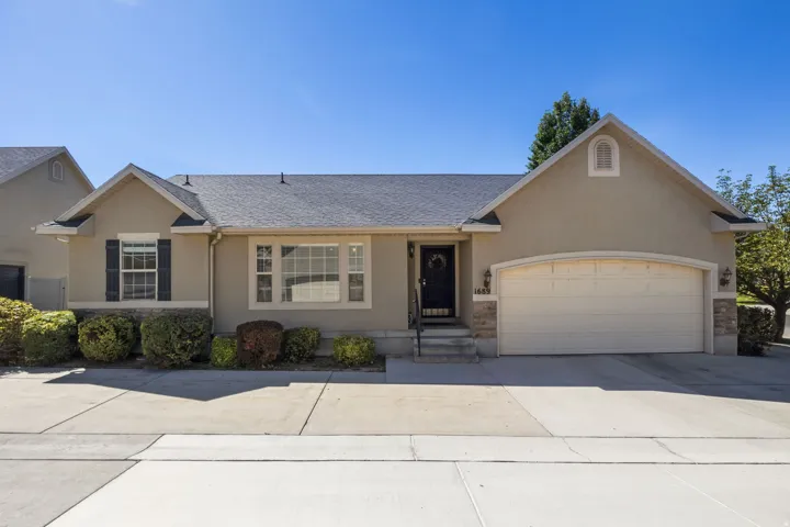 Stucco exterior with stone accents, attached garage, covered entry, and decorative shutters