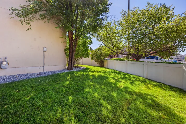 Manicured lawn with mature shade trees, bordered by a privacy fence and decorative rock landscaping