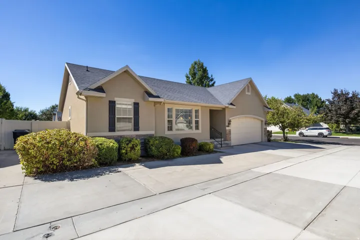 Stucco exterior with stone accents, a dark shingle roof, a two-car garage, and a concrete driveway
