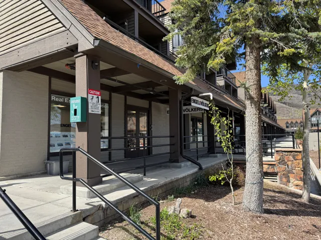 Commercial storefronts with large display windows, a covered walkway, and a sloped roofline