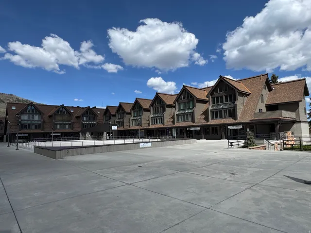 Multi-story structure featuring a pitched roofline, dormer windows, and a combination of stone and siding exterior finishes