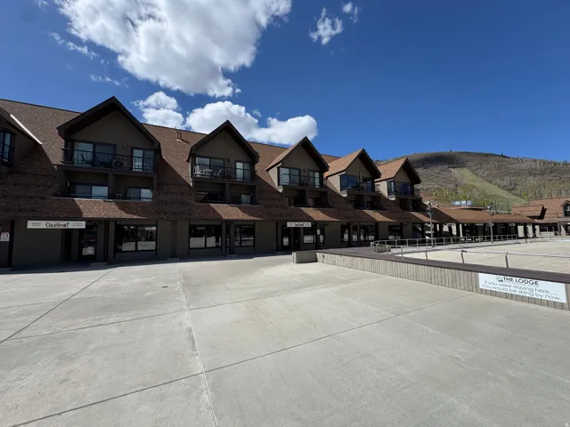 Multi-story building featuring multiple balconies, gabled rooflines, and ground-level commercial spaces