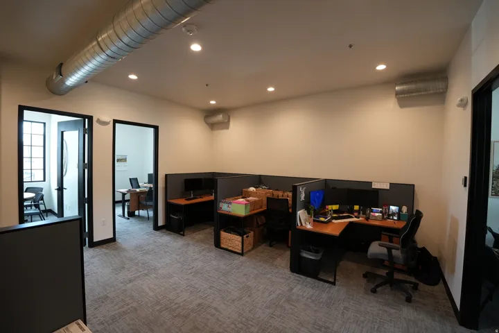 Recessed ceiling lighting, exposed spiral ductwork, and modular carpet flooring