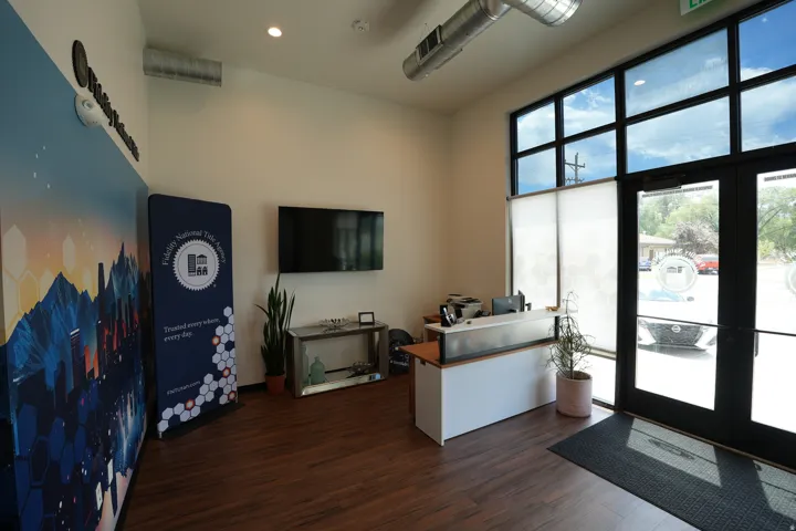 Reception area featuring wood-finish flooring, a built-in reception desk, and expansive windows with roller shades
