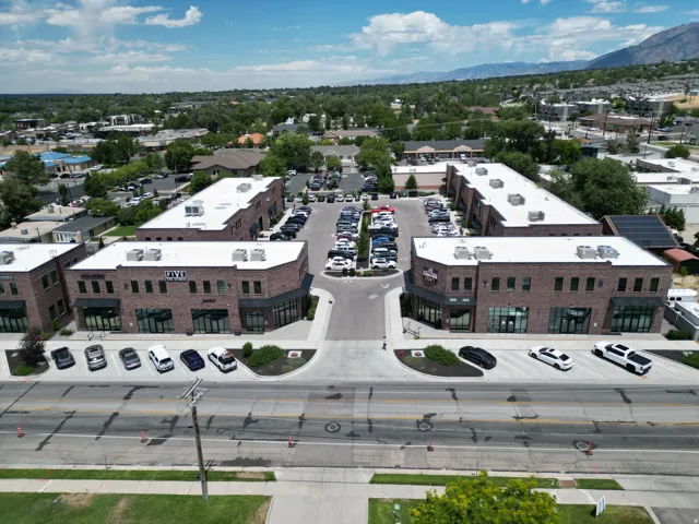 Two-story commercial buildings featuring brick facades, large storefront windows, and dedicated surface parking