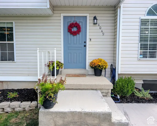 Welcoming front entry featuring a light blue six-panel door with black hardware, flanked by white railings and complemented by seasonal planters
