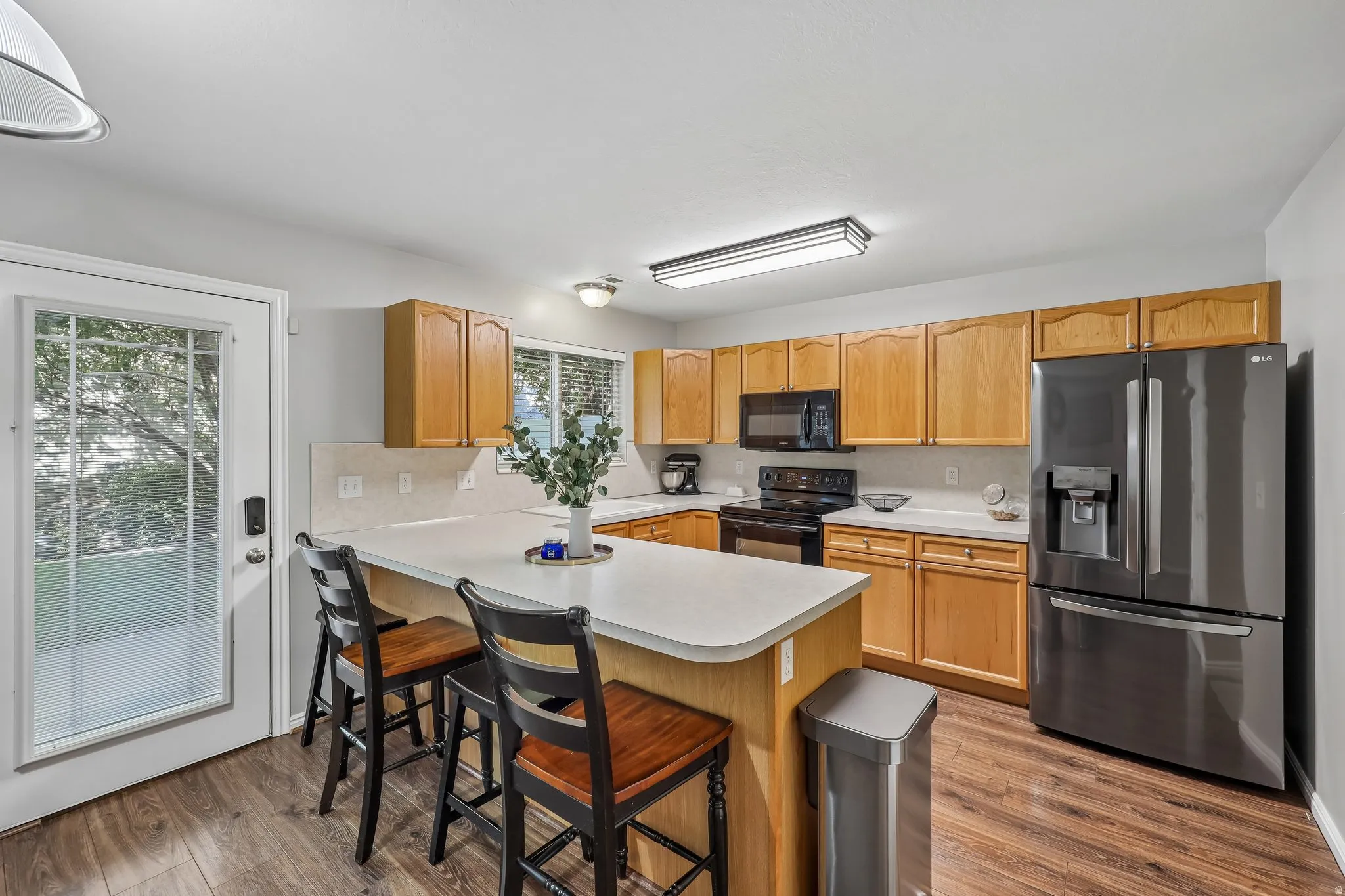 Well-appointed kitchen featuring wood-finish cabinetry, a central island, dark stainless steel appliances, and wood-finish flooring