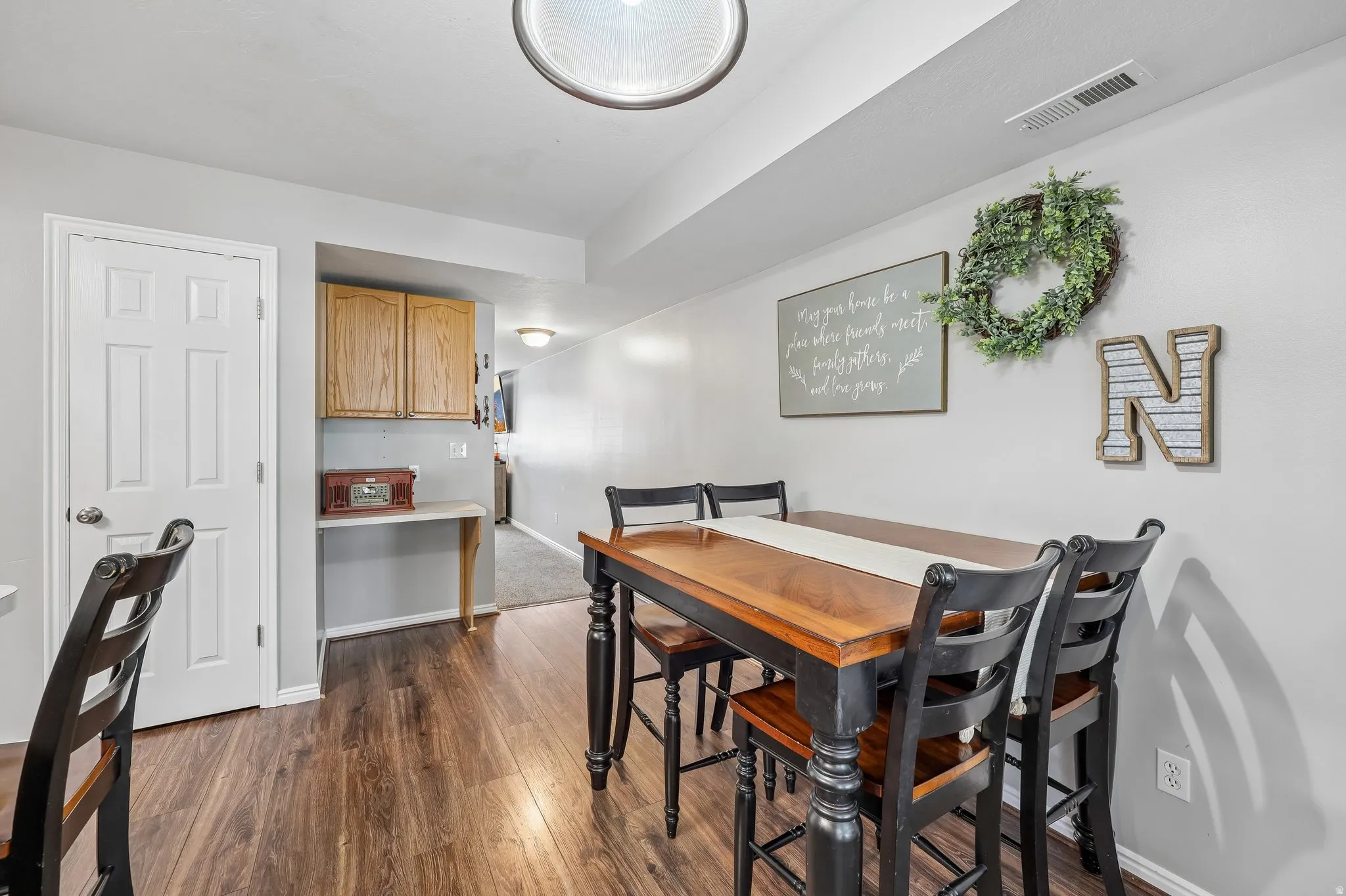 Wood-finish flooring throughout, light gray wall paint, and a built-in wood-finish cabinet with a countertop