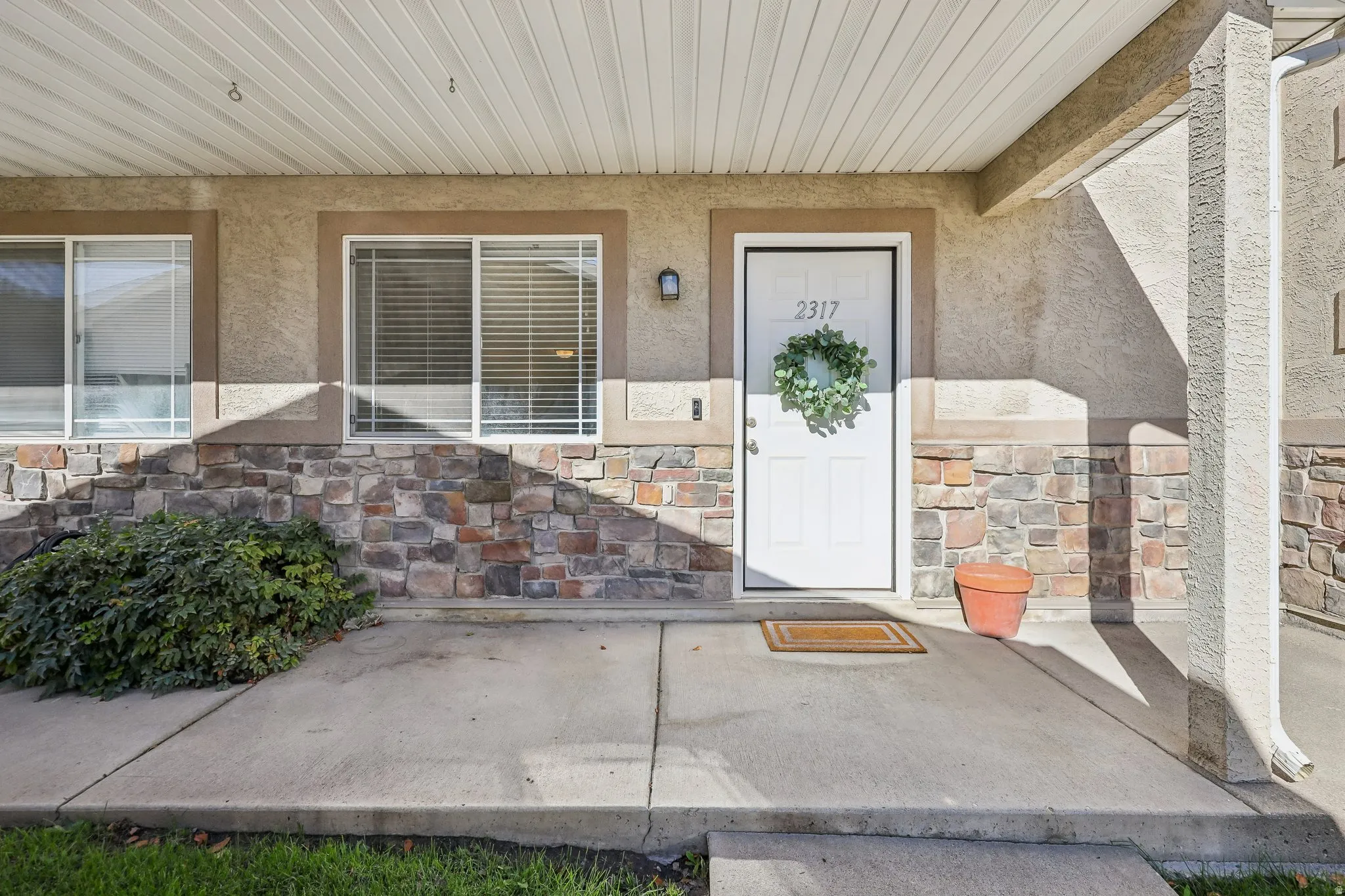 Stucco exterior with stone veneer accents, covered entry, and dual pane windows