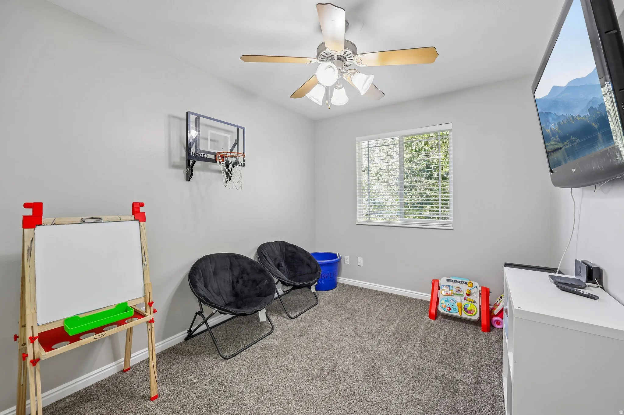 Carpeted room with a ceiling fan, window with blinds, and light gray walls