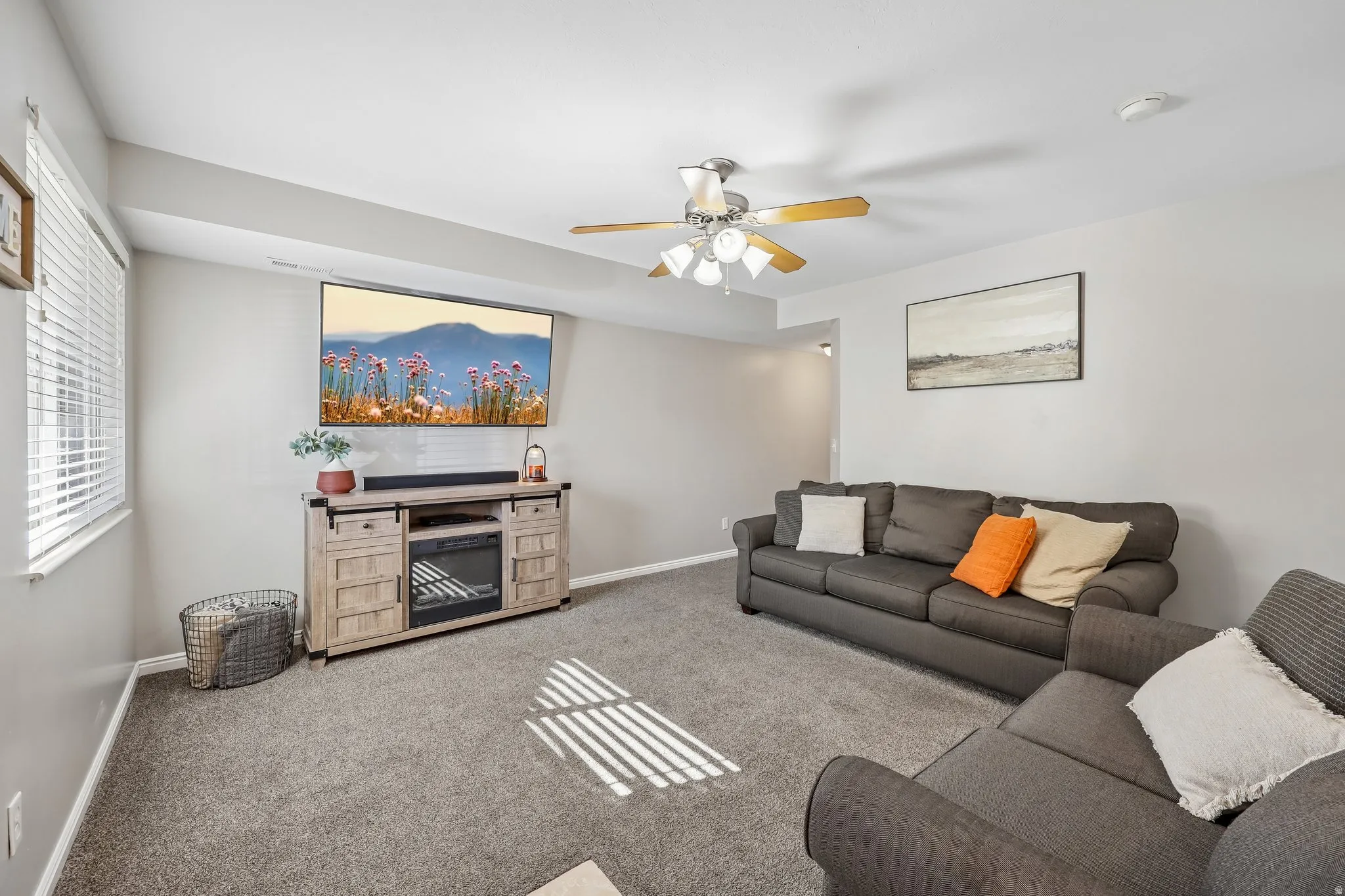 Carpeted living area featuring a ceiling fan with integrated lighting, a window with blinds, and light-toned walls