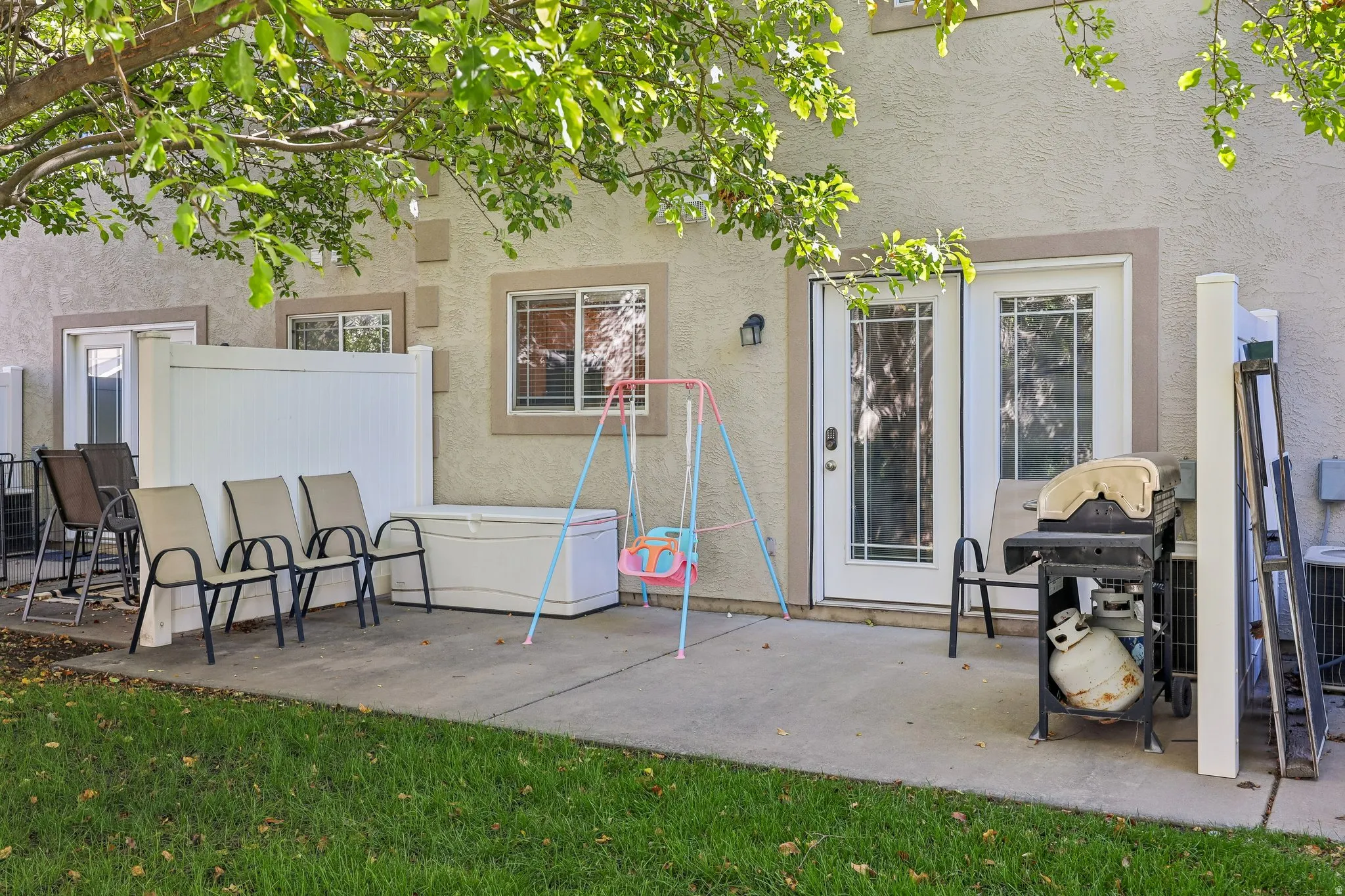 Private patio with a concrete surface, bordered by a white privacy fence and a manicured lawn