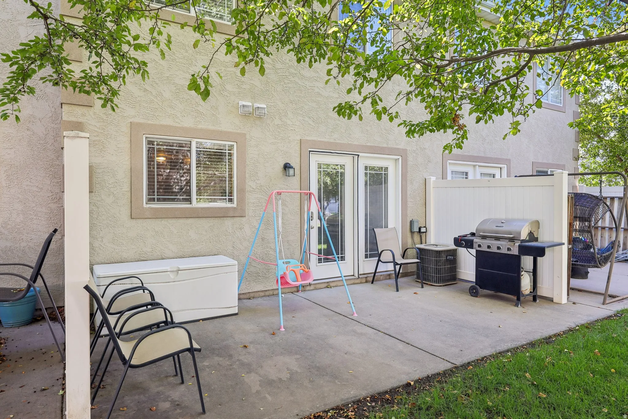 Concrete patio featuring a privacy fence, exterior lighting, and a stucco facade