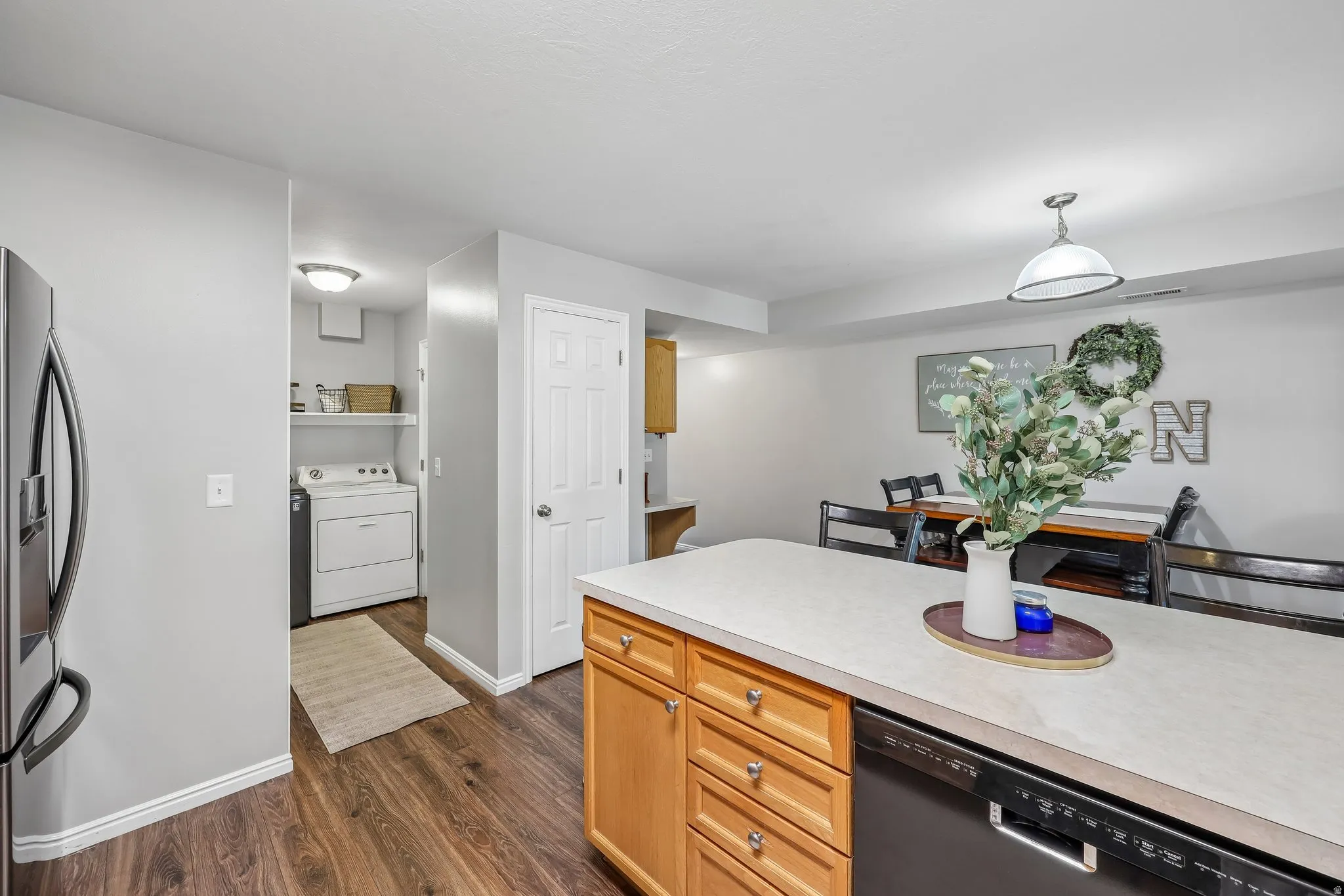 Kitchen island with light-toned countertop, wood-finish cabinetry, and integrated dishwasher