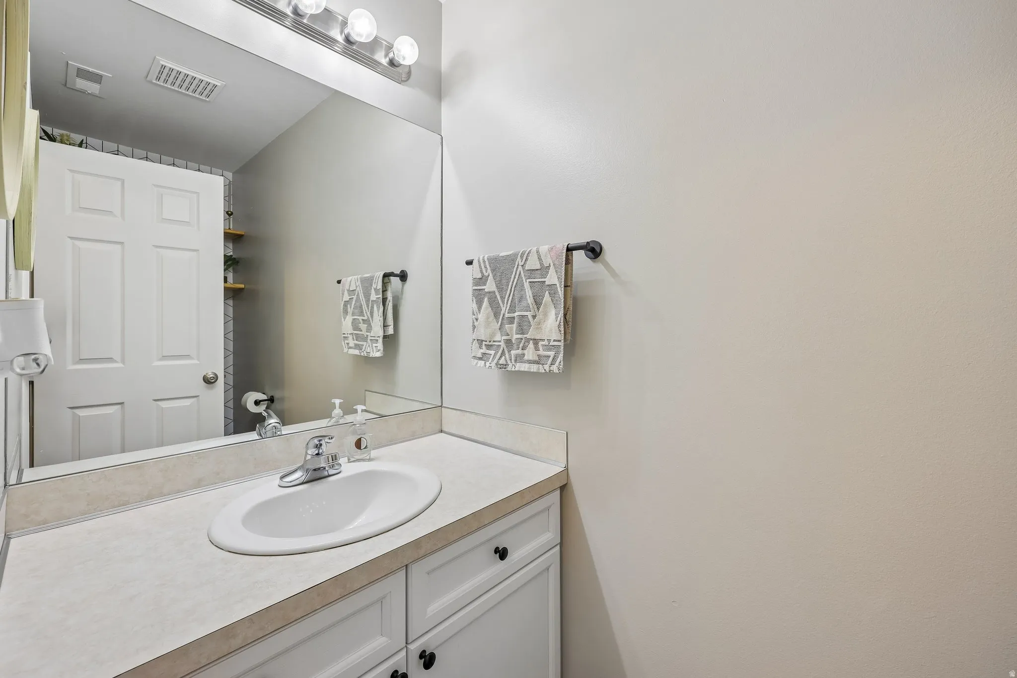 Vanity with white cabinetry, a single basin sink, and a light-colored countertop