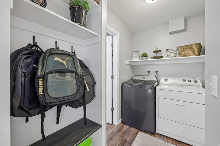 Laundry room featuring a top-load washing machine, front-load dryer, and wall-mounted shelving