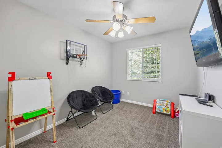 Carpeted room with a ceiling fan, window with blinds, and light gray walls
