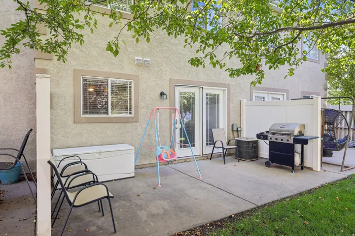 Concrete patio featuring a privacy fence, exterior lighting, and a stucco facade