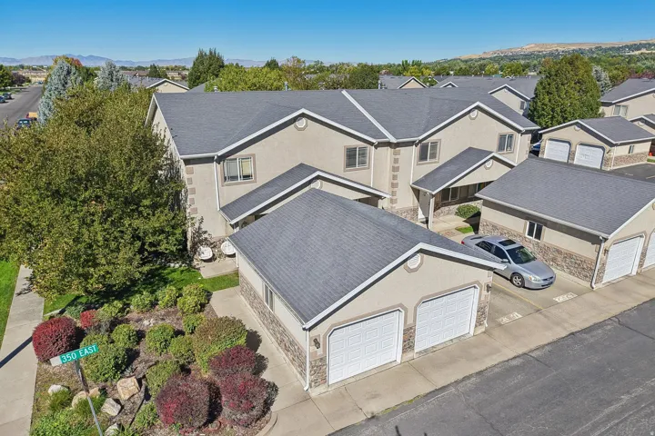 Stucco exterior with stone accent detailing, dual-panel garage doors, and mature landscaping
