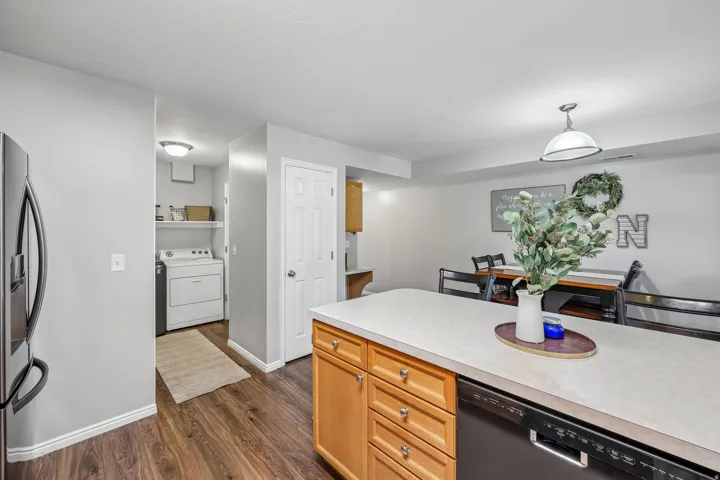 Kitchen island with light-toned countertop, wood-finish cabinetry, and integrated dishwasher