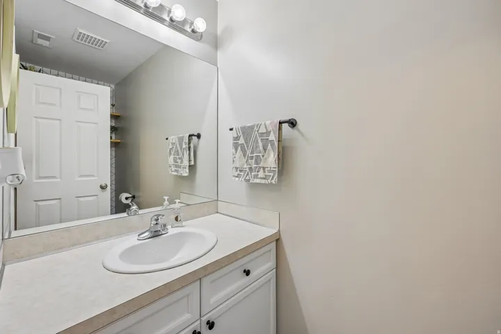 Vanity with white cabinetry, a single basin sink, and a light-colored countertop