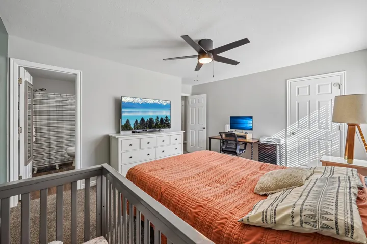 Recessed ceiling light, ceiling fan, wood-finish flooring, white paneled doors, and an open doorway to an adjoining room