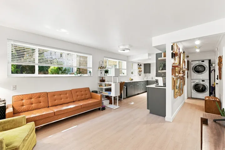 Open-concept living space and kitchen featuring custom cabinetry and a dedicated laundry area with stacked appliances