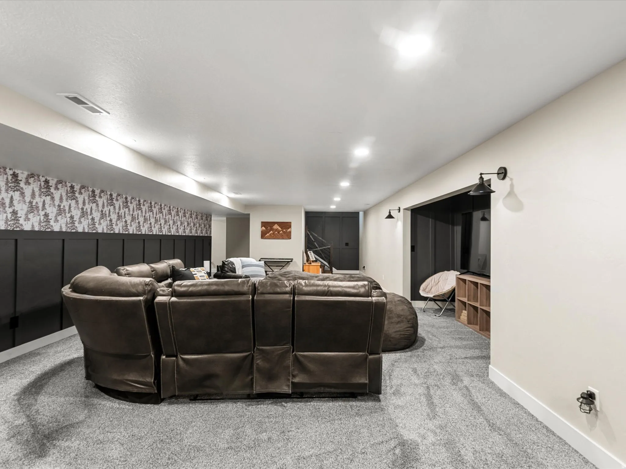 Carpeted entertainment space featuring recessed lighting, a built-in media niche, and wainscoting with patterned wallpaper