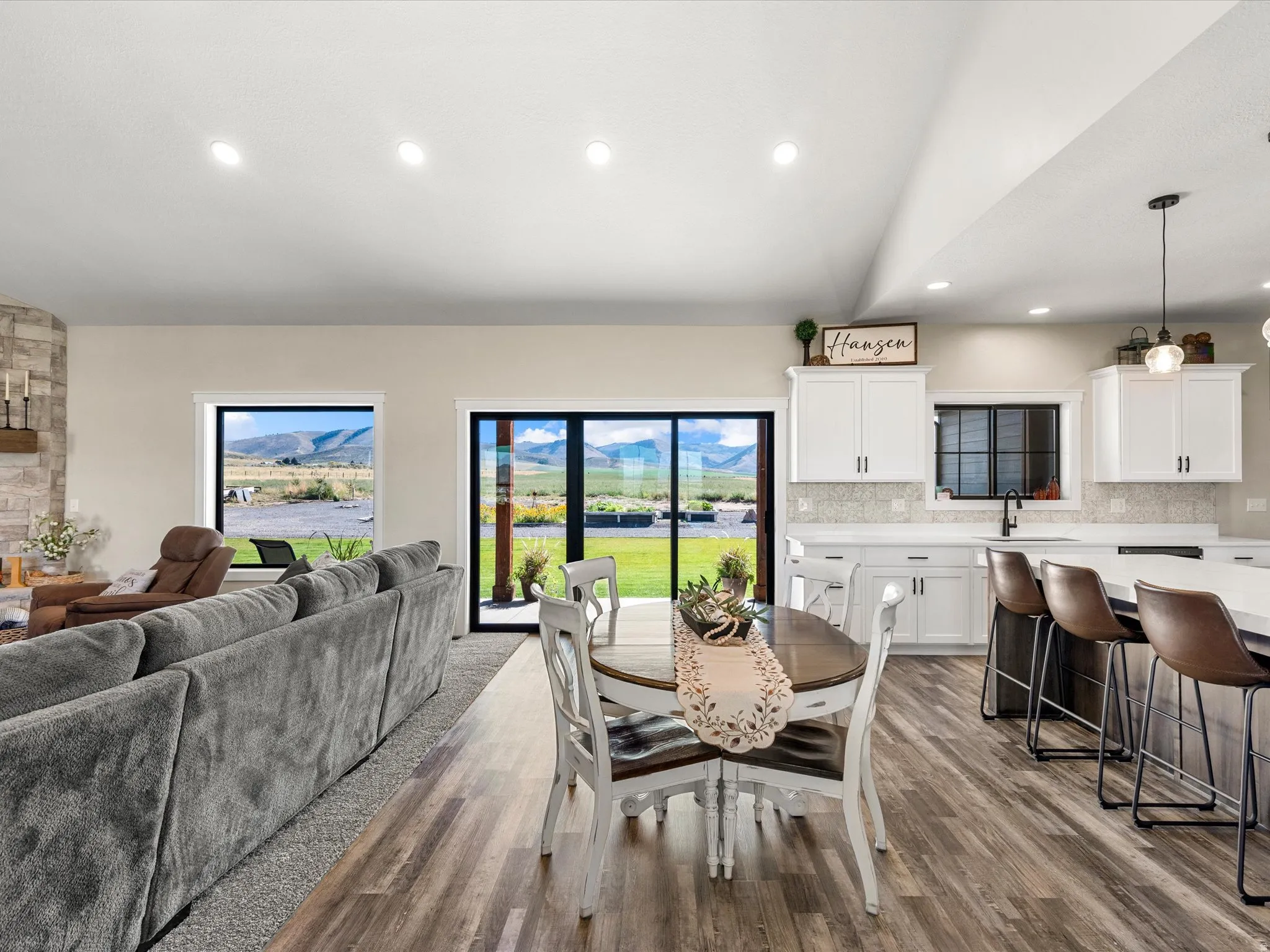 Open-concept living space featuring wood-finish flooring, recessed lighting, and a stone-clad fireplace