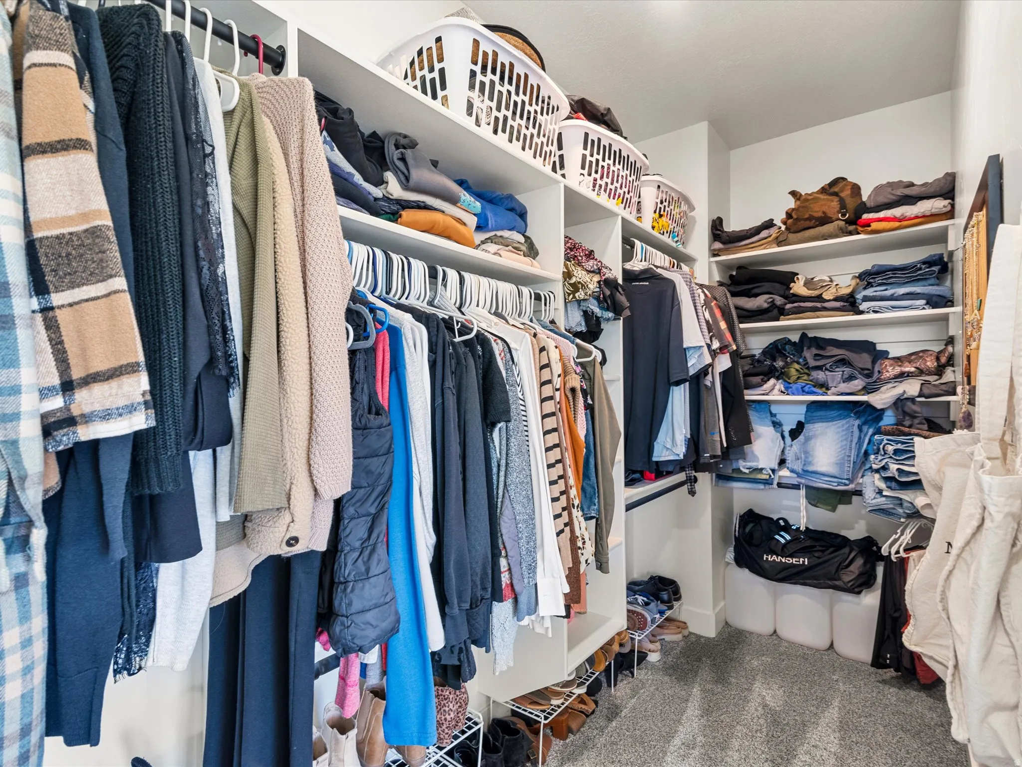 Custom closet system featuring multiple hanging rods, built-in shelving, and carpet flooring