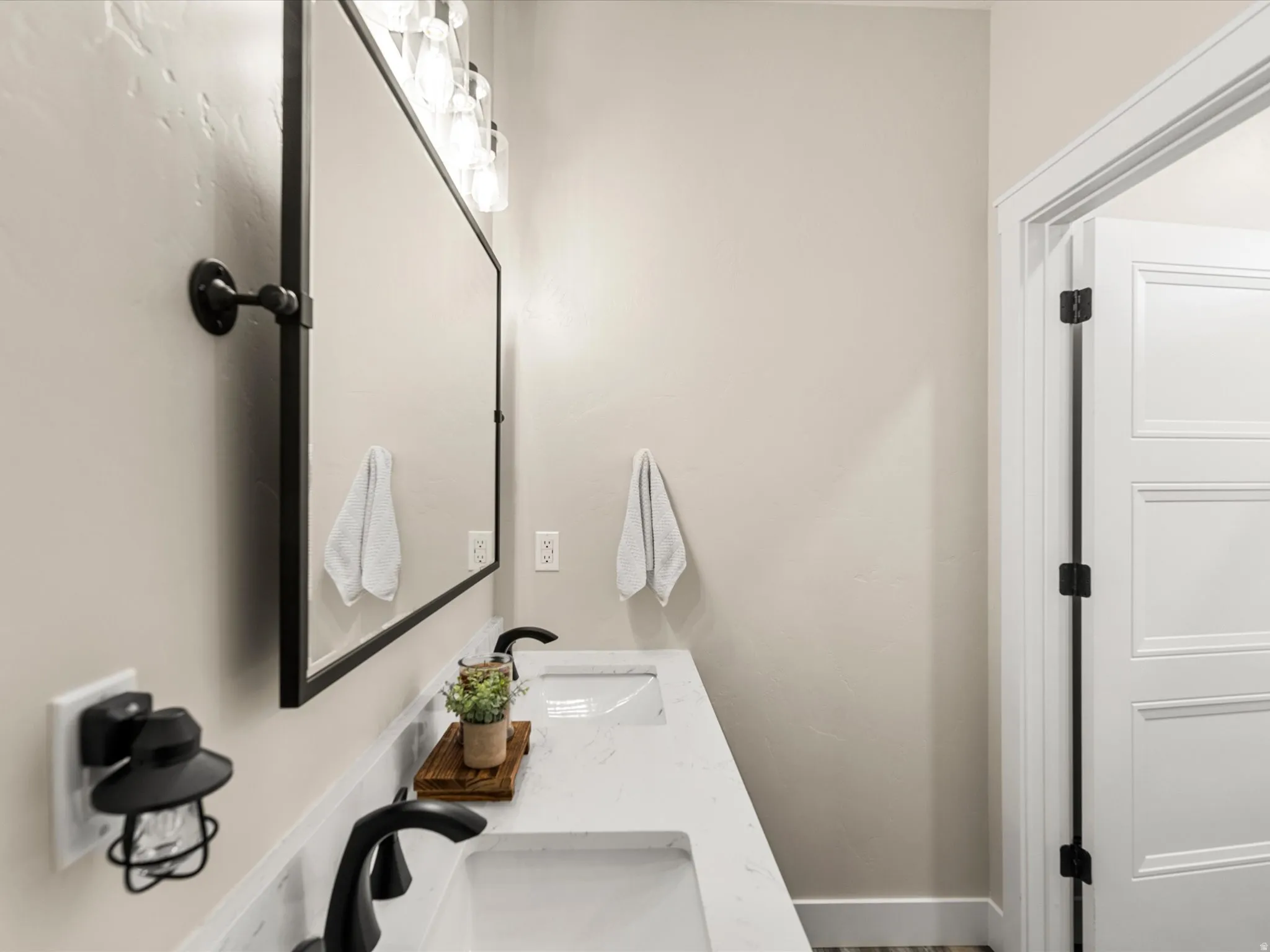 Dual vanity featuring integrated sinks, a continuous countertop, black-framed mirror, and modern light fixtures