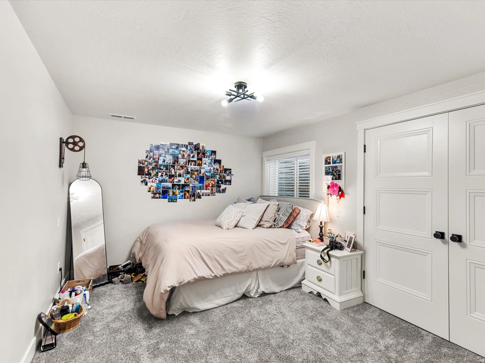Plush gray carpeting, white trim, and a window with horizontal blinds provide natural light