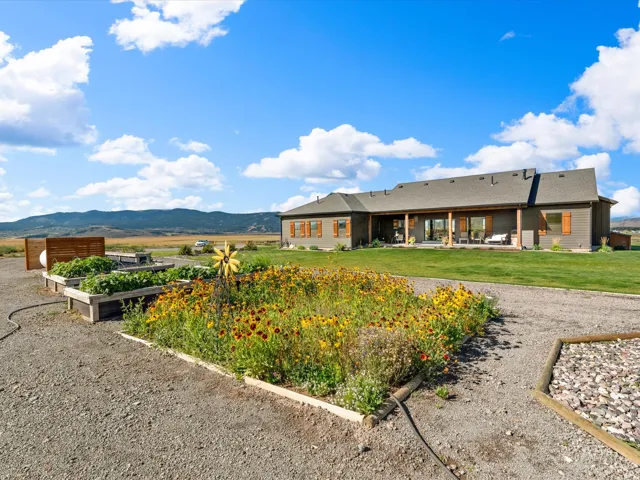 Expansive gravel driveway leading to a residence with a large covered patio