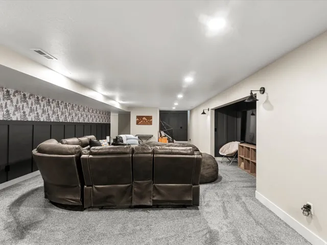 Carpeted entertainment space featuring recessed lighting, a built-in media niche, and wainscoting with patterned wallpaper