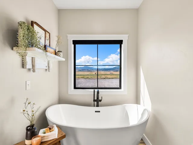 Freestanding white soaking tub with a matte black floor-mounted faucet