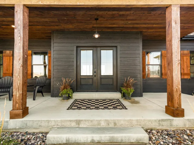 Covered front porch featuring robust wood columns, a wood-paneled ceiling, and dark wood-finish siding