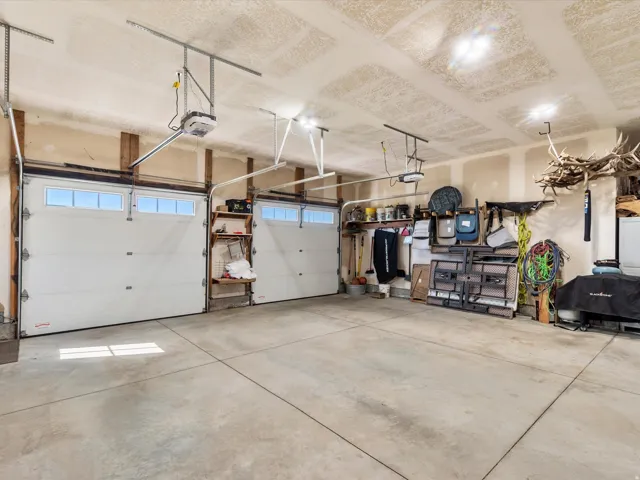 Two overhead garage doors with upper window panels, concrete flooring, and exposed wood structural beams