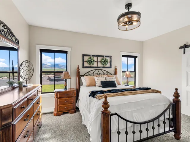 Vaulted ceiling, two large windows, ceiling-mounted light fixture, and carpeted flooring