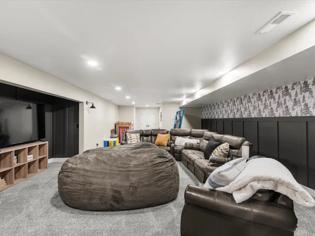 Recessed lighting, light gray carpeting, and a dark accent wall with board and batten paneling