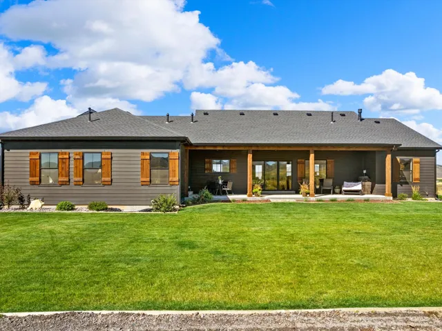 Exterior siding with wood-finish shutters, covered patio with wood beams, and a concrete patio surface