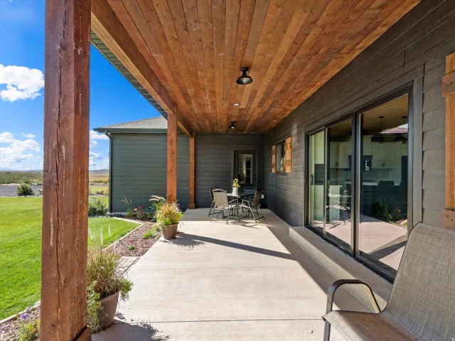 Expansive concrete patio featuring a wood-finish ceiling, dark-toned siding, and large sliding glass doors