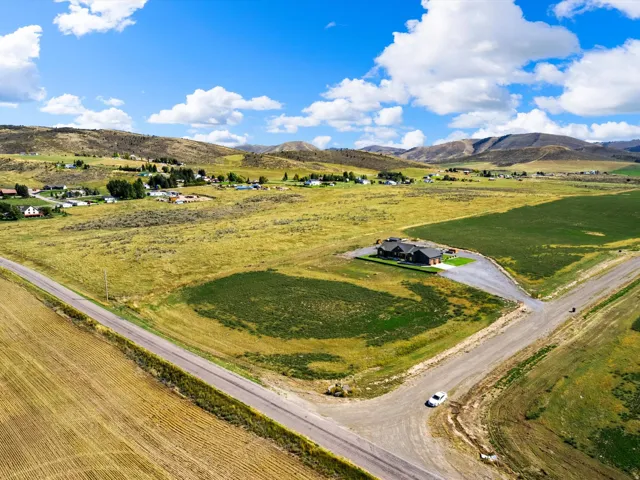 Expansive rural property featuring a large residence, surrounding green fields, and distant mountainous terrain
