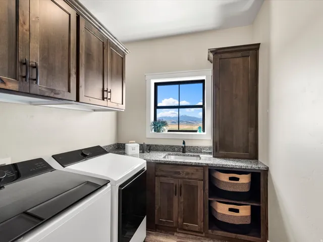 Dark wood-finish cabinetry, granite-style countertops, stainless steel sink with a dark-finish faucet, and an integrated window