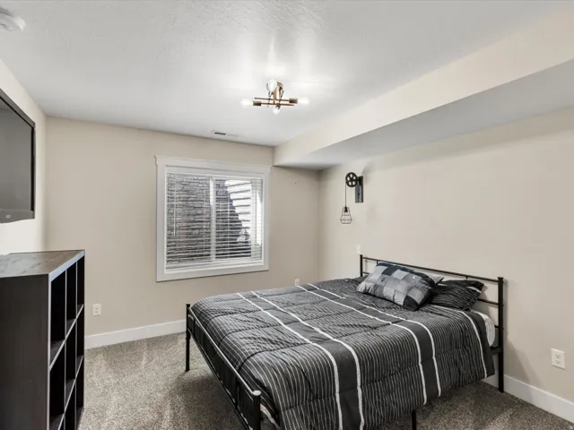 Recessed window with blinds, ceiling-mounted light fixture, and textured carpet flooring