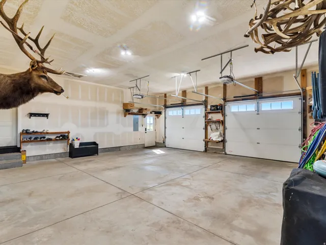 Concrete flooring garage featuring two white panel garage doors with upper window panes