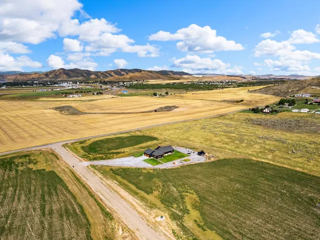 Expansive parcel featuring a single-story residence with a dark-toned exterior and a surrounding gravel driveway